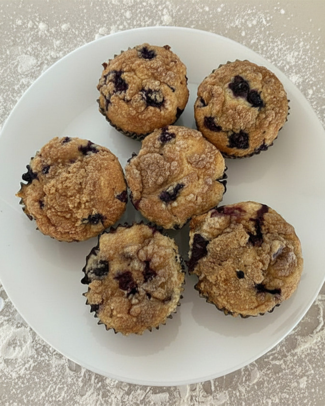 Six homemade blueberry muffins on a white plate. 